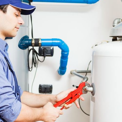 A plumber works n an electric water heater.