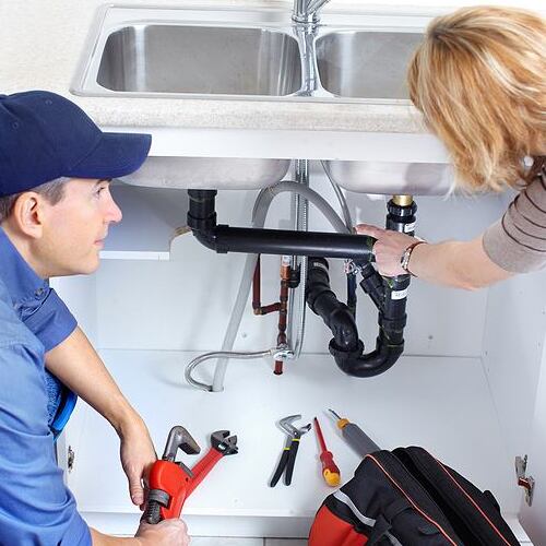 A plumber examines pipes.
